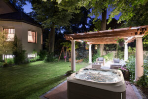 Outdoor pool and hot tub installation at night with lights under a pergola.