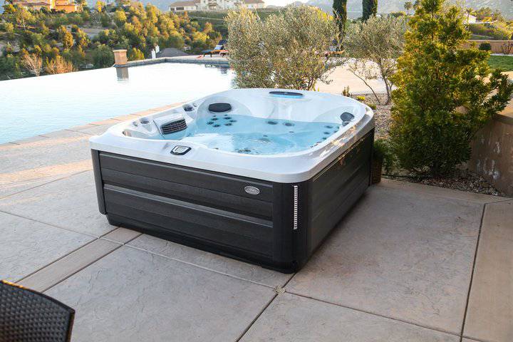 hot tub service - a jacuzzi hot tub on a stone patio with a pool in the background